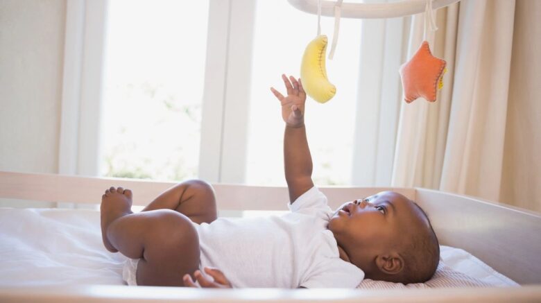 African American baby in white onesie in crib