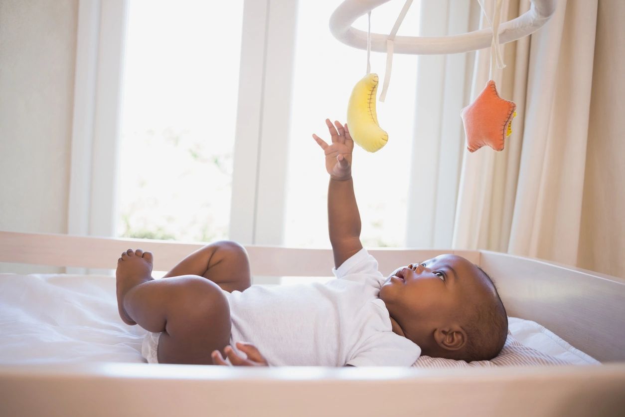 African American baby in white onesie in crib